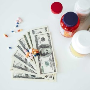 Picture of money with pills and vitamins over white background